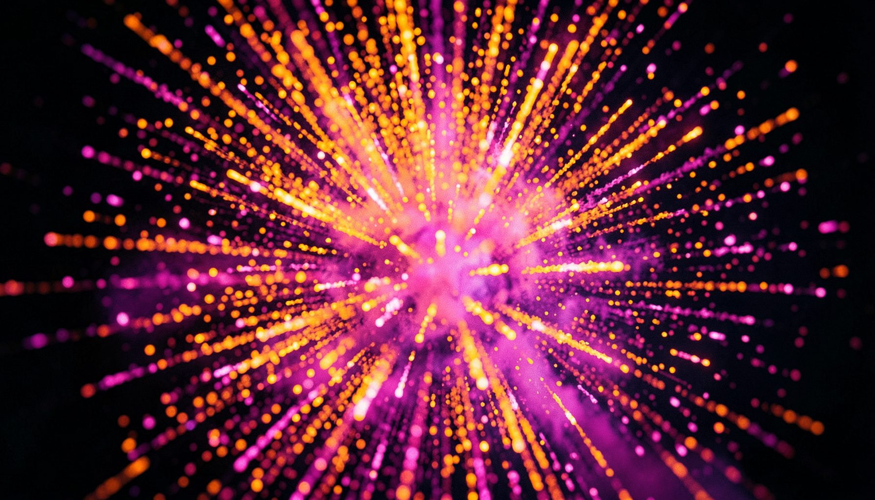 Vibrant burst of orange and pink particles radiating outward against a dark background, evoking an explosion effect
